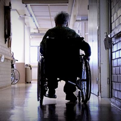 Vanhus istuu pyörätuolissa hoitolaitoksen käytävällä