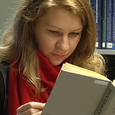 Nainen lukee venäjänkielistä kirjaa yliopiston kirjastossa.