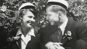 Suomisen Olli yllättää. Olli (Lasse Pöysti) ja Laura (Sirkka Osmala) hymyilevät valkolakit päässään elokuvassa Suomisen Olli yllättää