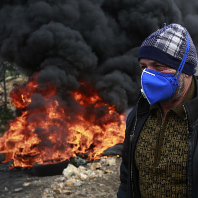 En palestinsk demonstrant passerar en brinnande barrikad utanför en israelisk bosättning nära staden Nablus på Västbanken.