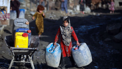 En afghansk flicka i ett flyktingläger i huvudstaden Kabul hämtar vatten från en tankbil.