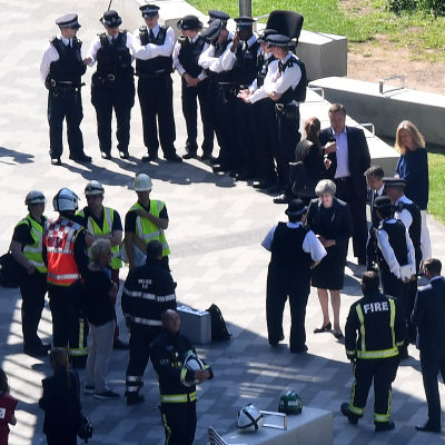 Theresa May omgiven av poliser vid olycksplatsen för höghusbranden.