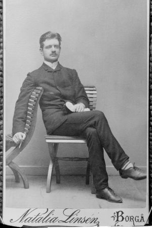 Nuori Jean Sibelius valokuvaajalla ylioppilaslakki sylissään.