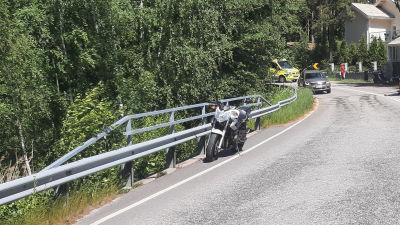 En motorcykel står vid sidan av Skärgårdsvägen, en ambulans i bakgrunden.