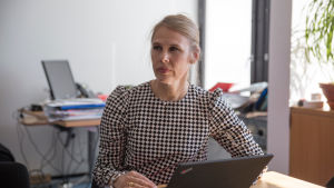 Enligt Leena Turpeinen utreder man nu upplevelser från Fiskehamnens vårdcentral. Staden är ändå inte ännu redo att slopa den nya verksamhetsmodellen. En kvinna som sitter vid ett skrivbord med en dator framför sig.