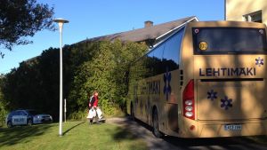 Röda korsets Veli-Matti Salo hjälpte att bära in resväskorna. polisbil och buss