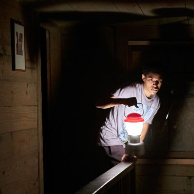 Travis (Kelvin Harrison Jr.) med lykta i handen smyger fram i en mörk korridor.