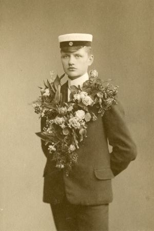 Carl Nyman som nybliven student. Carl Nymans studentfoto där han står med allvarlig min och en enorm blomsterklass runt halsen.