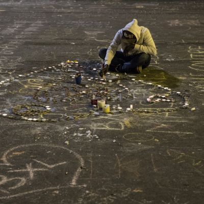 Nuori mies sytyttää kynttilöitä Place de la Boursen aukiolla Brysselissä uhrien muistoksi.