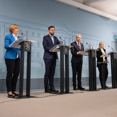 Foto på avstånd av fyra ministrar i presskonferens.