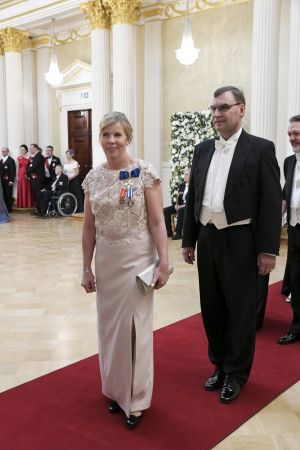 Anna-Maja Henriksson redo att skaka tass, tillsammans med maken Janne Johannes Henriksson. Anna-Maja Henriksson är klädd i vit klänning.