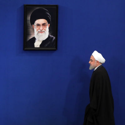Irans president Hassan Rouhani går förbi ett foto på den högsta ledaren Ali Khamenei
