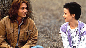 Gilbert Grape. Mies ja nainen istuvat maassa ja katsovat toisiaan. Miehellä on ruoho suussa.