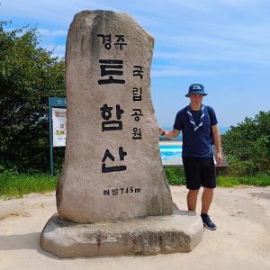 En manlig ung scout står vid ett sydkoreanskt minnesmärke vid berget Tohamsan och tittar in i kameran.