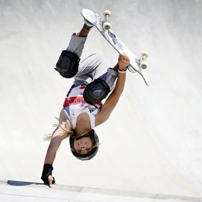 Skateboardare i vit dräkt gör ett trick under sitt åk.
