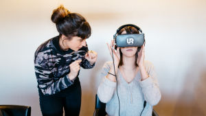 Saskia Oljelund näyttää UR:n tekemää koulukiusaamis-videoita, VR-silmikko päässä Jenna Karas