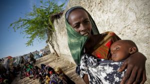 En somalisk kvinna håller i sitt svårt undernärda barn. Somalisk kvinna med sitt svårt undernärda barn utanför en klinik i Modadishu