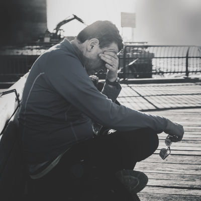 En medelålders man sitter ute i en hamn