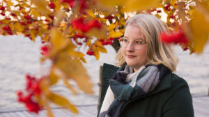 Julen är som en egen årstid tycker Linda. En blond kvinna med glasögon. Står framför en rönn med röda bär. I bakgrunden syns havet.