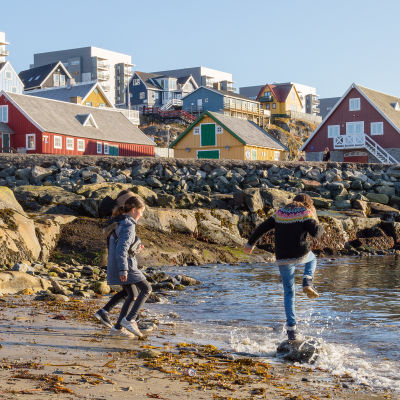 Två barn leker på en strand i Nuuk, Grönland.