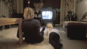 Nainen ja lapsi katsovat televisiota olohuoneen lattialla. Kuva otettu vuonna 1983.
