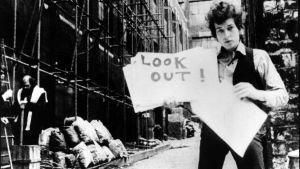 Bob Dylan esittelee sanakylttejä "musiikkivideossa" Subterranean Homesick Blues, taustalla Allen Ginsberg. Kuva D.A. Pennebakerin ohjaamasta dokumenttielokuvasta Don't Look Back (1967).