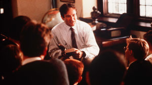 Filmen “Döda poeters sällskap” (1989) med Robin Williams, där en gammal privatskolsmiljö gestaltas är popular inom dark academia. Scen ur filmen "Döda poeters sällskap". Robin Williams sitter med en bok i sin hand i ett klassrum.