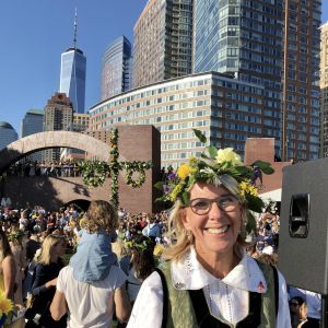 Generalkonsul Annika Rembe med midsommarstång och World Trade Center i bakgrunden Sveriges generalkonsul Annika Rembe på midsommarfest i skånsk folkdräkt och blommor i håret i New York.