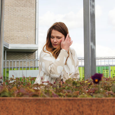 Kuvassa ympäristöbiologi Taina Suonio, etualalla kukkapenkki, jossa orvokkeja.