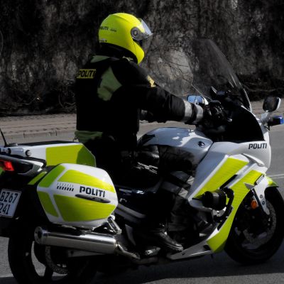 En dansk polis på polisens motorcykel. Det står polis på danska på motorcykeln.