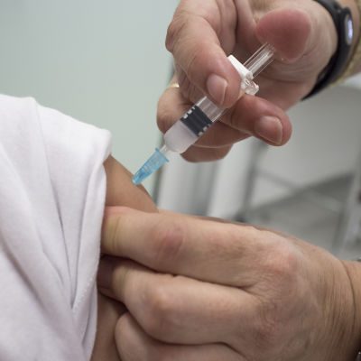 Läkare vaccinerar patient i armen.