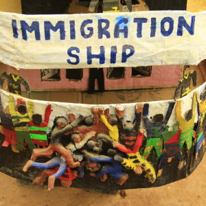 Bak på Immigration Ship kämpar immigranterna om att få komma ombord. Bak på the Immigration Ship hänger Afrianska flyktingar