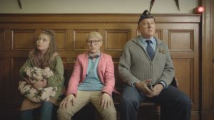 Hm, det är inte alltid så lätt att lösa mysterier tänker Maja (Ester Vuori), Lasse (Frank Dorsin) och polismästaren (Tomas Norström). Maja (Ester Vuori), Lasse (Frank Dorsin) och polisen (Tomas Norström) sitter på en bänk och ser fundersamma ut.
