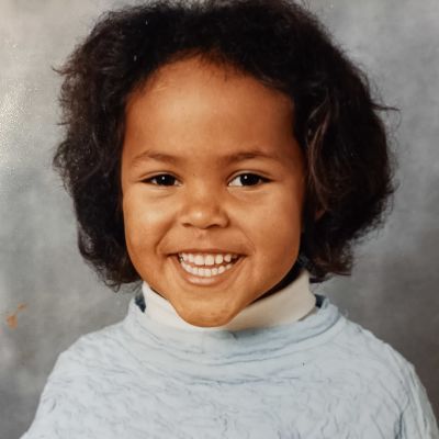 Elina som barn på ett dagisfoto. Hon ler stort.