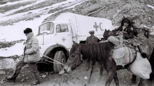 Azerier flyr österut från gränsområdet mot Armenien under kriget på 1990-talet. Ett barn på en häst bredvid en vit lastbil med Röda korsets och Röda halvmånens emblem.