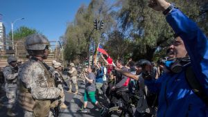 För första gången sedan Augusto Pinochets militärdiktatur upphörde 1990 patrulleras gatorna av militären. Den här bilden visar demonstranter och soldater på en gata i Santiago på söndagen. För första gången sedan Augusto Pinochets militärdiktatur upphörde 1990 patrulleras gatorna av militären. Den här bilden visar demonstranter och soldater på en gata i Santiago på söndagen.