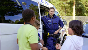 Många är nyfikna på polisens jobb. Polisen Nicolai diskuterar med tre barn som är intresserade av polisyrket. En polis och tre barn står framför en polisbil och pratar.