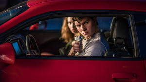 Nej Baby - du behöver inte skjuta, det här är sommarens snärtigaste film. Baby (Ansel Elgort) och Debora (Lily James) sitter i en bil och Baby siktar med en pistol ut genom bilfönstret.