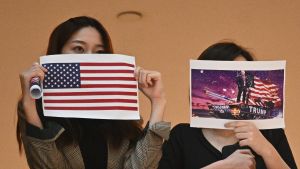 Många demonstranter i Hongkong hoppas på hjälp från USA Två demonstranter håller upp bilder på USA:s flagga och president Donald Trump