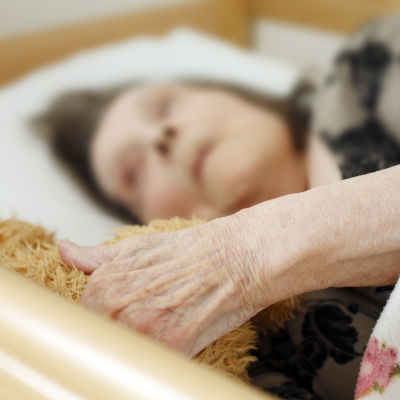 Äldre kvinna ligger i en säng.