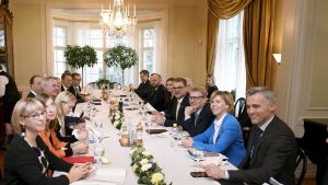 Representanter för alla partier sitter samlade i statsministerns tjänstebostad kring ett bord med vit duk och takkrona.