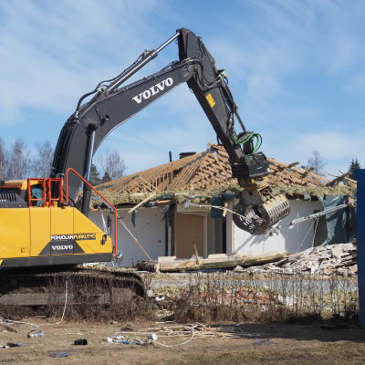 Kaivuri purkaa vuokrataloyhtiön rakennusta.