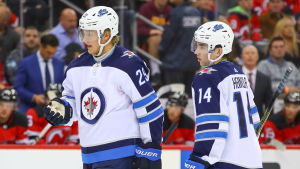 Både Patrik Laine och Ville Heinola har fått lyckade starter på säsongen. Patrik Laine håller upp en hand i luften och Ville Heinola tittar på.