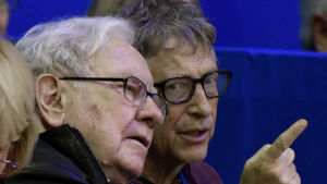 Gates&Buffett Bill Gates och Warren Buffett trängs på en åskådarbänk på hästhoppstävling. Buffett pekar på något utanför bilden.