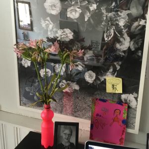 Blommor och den rosa färgen inspirerar Sanna Mander. En blombukett framför ett konstverk.