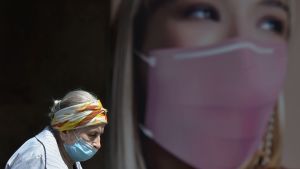 En äldre kvinna iförd ansiktsmask går förbi en reklamskylt som uppmanar ukrainarna att skydda sig från coronaviruset