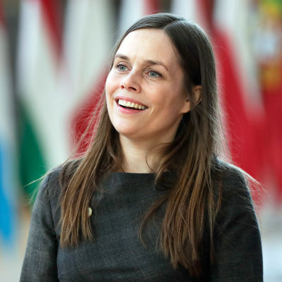 Katrin Jakobsdottir ler och tittar åt sidan. I bakgrunden syns flera flaggor på rad.