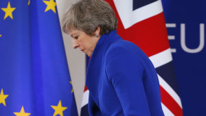 Storbritanniens premiärminister Theresa May framför en EU:s och Storbritanniens flaggor