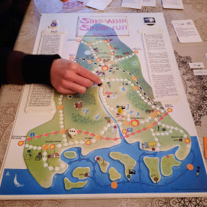 På den tredimensionella spelplanen är Östersundom fortfarande en del av Sibbo. Bild på ett brädspel föreställande Sibbo och en hand som flyttar en spelpjäs.