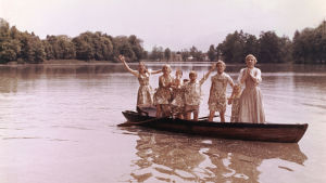 Maria (Julie Andrews) och barnen von Trapp, när de alla ännu är i båten. Maria (Julie Andrews) och alla von Trapp-barnen står upp i en roddbåt.